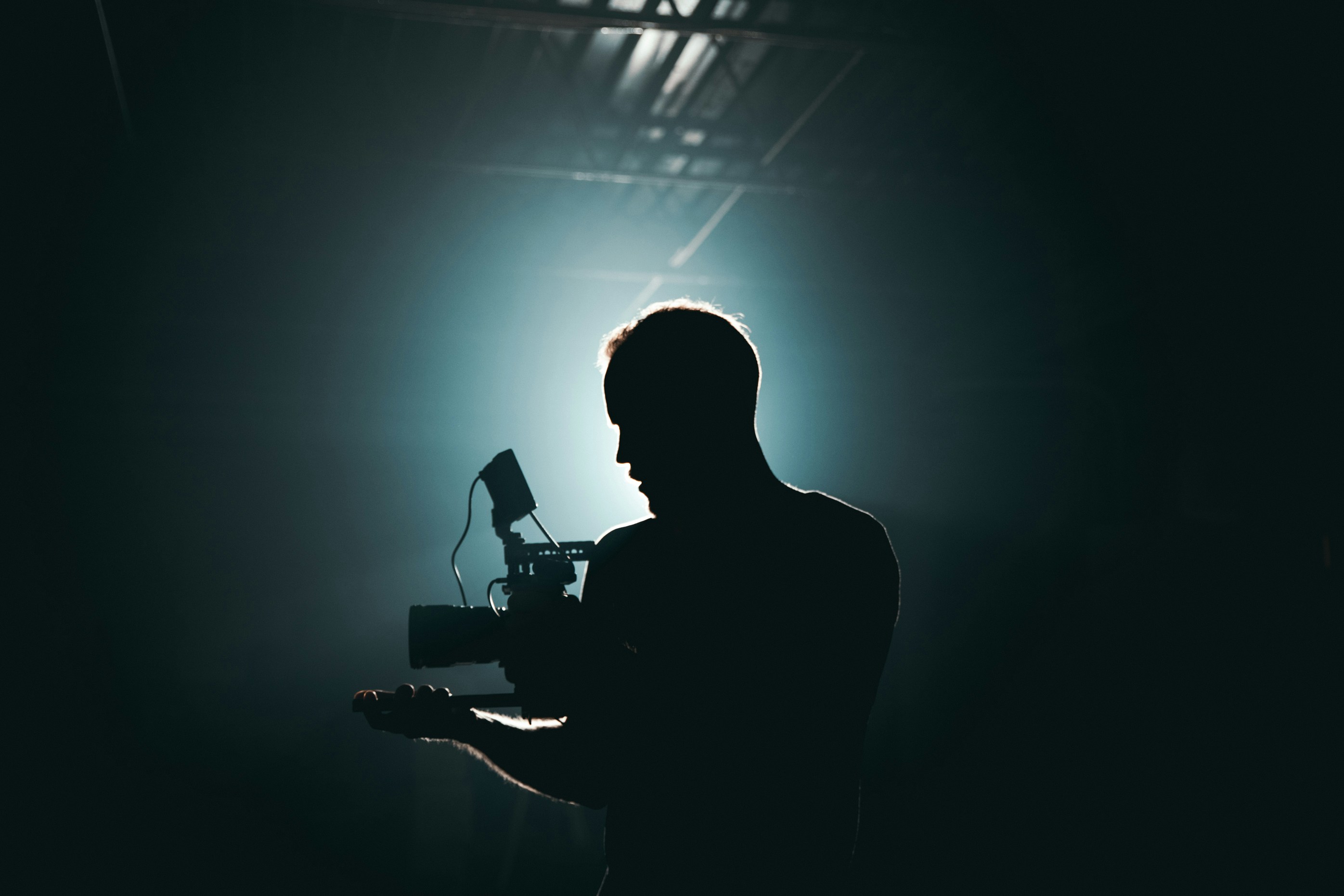Backlit silhouette of a man holding a guitar.