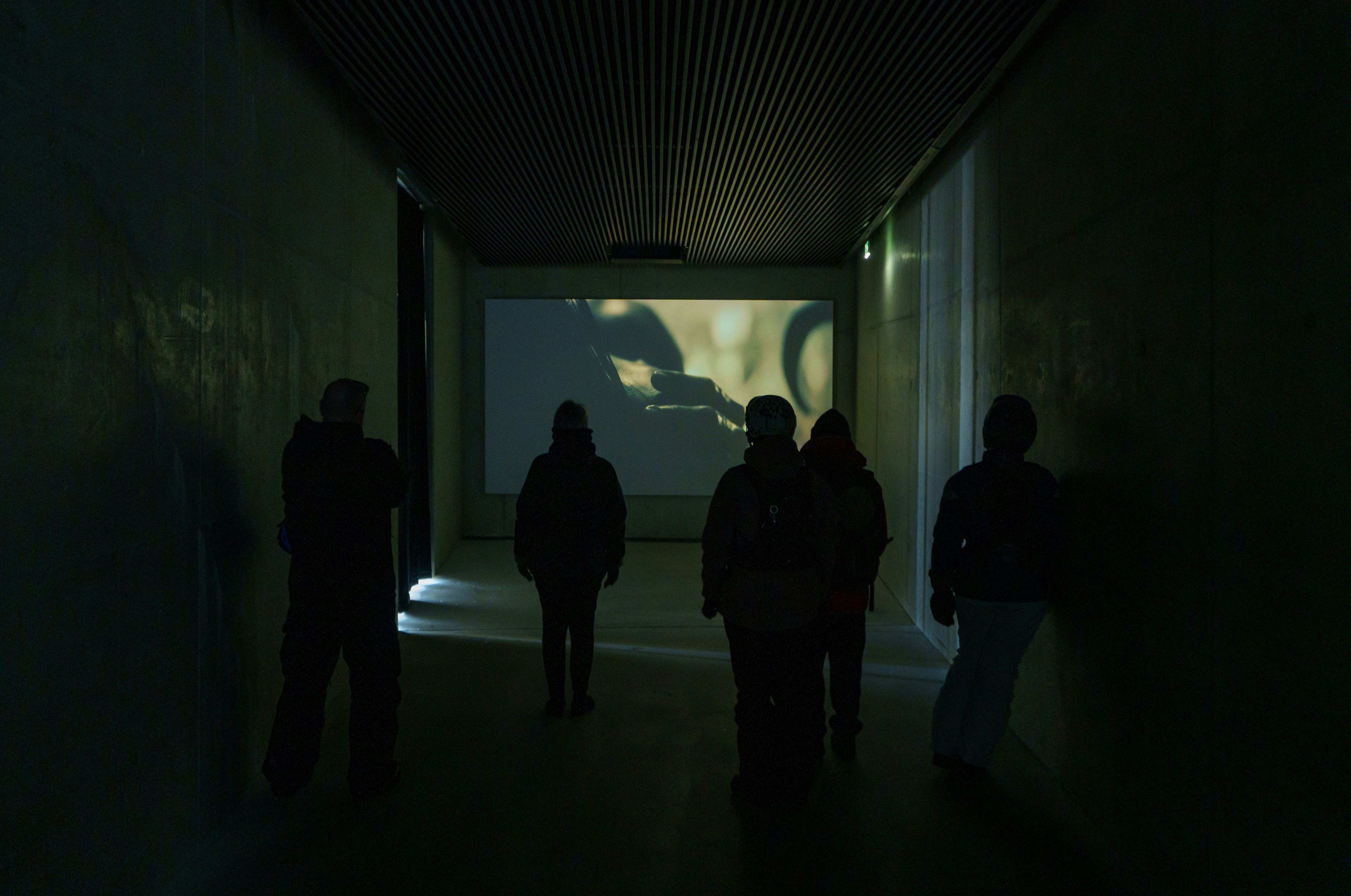 Group of 5 adults standing in an empty industrial hallway walking away.